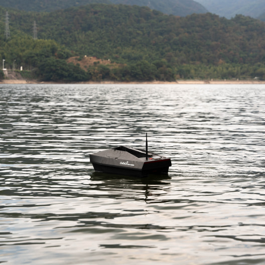 Remote control bait boat floating on calm lake waters - GPS-enabled fishing bait boat for carp fishing and bait dropping