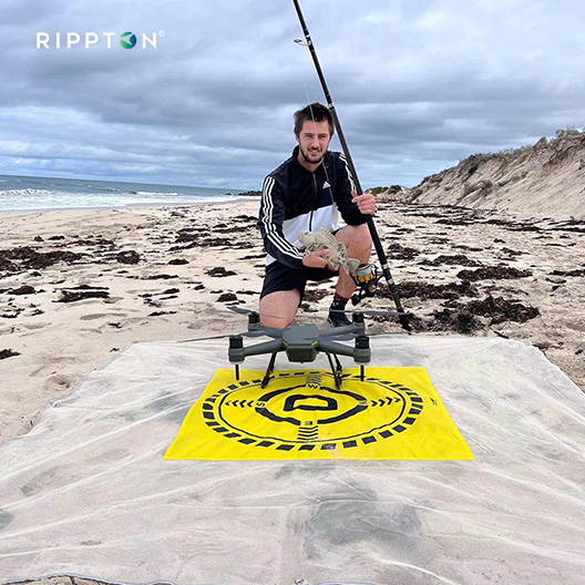 Person using SharkX waterproof drone surf fishing with bait release on a beach, showcasing drone for professional capabilities